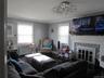 Living room featuring radiator, plenty of natural light, wood finished floors, a tiled fireplace, and crown molding