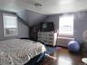 Bedroom with radiator heating unit, wood finished floors, lofted ceiling, a chandelier, and cooling unit