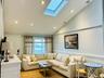 Living room featuring vaulted ceiling, recessed lighting, a skylight, and a wainscoted wall