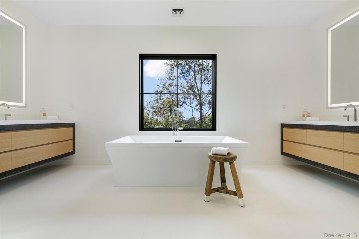 Bathroom featuring two vanities, a freestanding bath, and light tile patterned floors