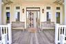 View of exterior entry featuring stucco siding and large mahogany front deck