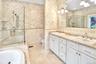 Full bathroom featuring tile walls, double vanity, a bathtub, a stall shower, and light tile patterned floors