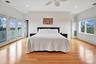 Second Floor Primary Bedroom with stunning ocean and bay surround views, featuring crown molding, light wood-type flooring, access to exterior, a ceil