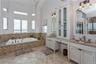 Bathroom with tiled bath, an inviting chandelier, and vanity
