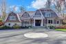 Shingle-style home featuring a gambrel roof and stone siding