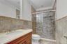 Basement Full bath featuring tile walls, vanity, crown molding, a stall shower, and a wainscoted wall