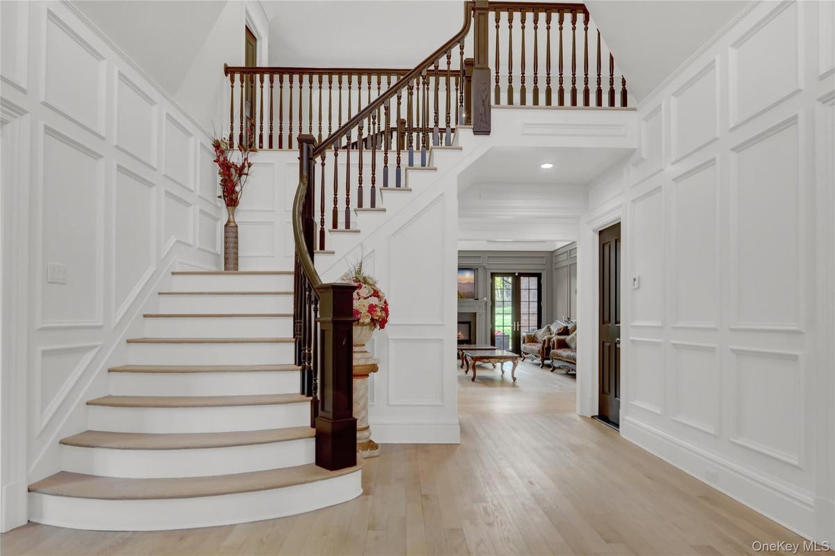Stairs with a decorative wall, a high ceiling, and wood finished floors