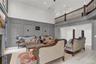 Living room featuring a decorative wall, a towering ceiling, ornamental molding, wood finished floors, and a glass covered fireplace