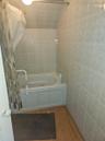 Bathroom with tile walls, wood finished floors, and shower / tub combo with curtain