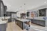 Kitchen with tasteful backsplash, a center island with sink, ornamental molding, light stone counters, and high quality appliances