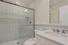 Full bathroom featuring vanity, ornamental molding, a shower stall, and wainscoting