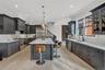 Kitchen featuring backsplash, glass insert cabinets, decorative light fixtures, light stone counters, and a kitchen island