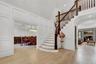 Staircase featuring a decorative wall, hardwood / wood-style floors, a towering ceiling, and a warm lit fireplace
