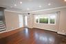 Unfurnished living room featuring crown molding, dark wood-type flooring, recessed lighting, a baseboard radiator, and stairway