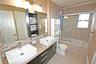 Full bath featuring double vanity, tiled shower / bath combo, decorative backsplash, light tile patterned floors, and a baseboard radiator