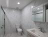 Full bath featuring a marble finish shower, tile walls, vanity, and marble tiled floors