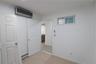 Interior room featuring wood-finish flooring, a wall-mounted ductless climate control unit, a sliding-door closet, and a horizontal transom window