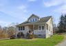 Bungalow-style home featuring a front lawn, covered porch, and a shingled roof