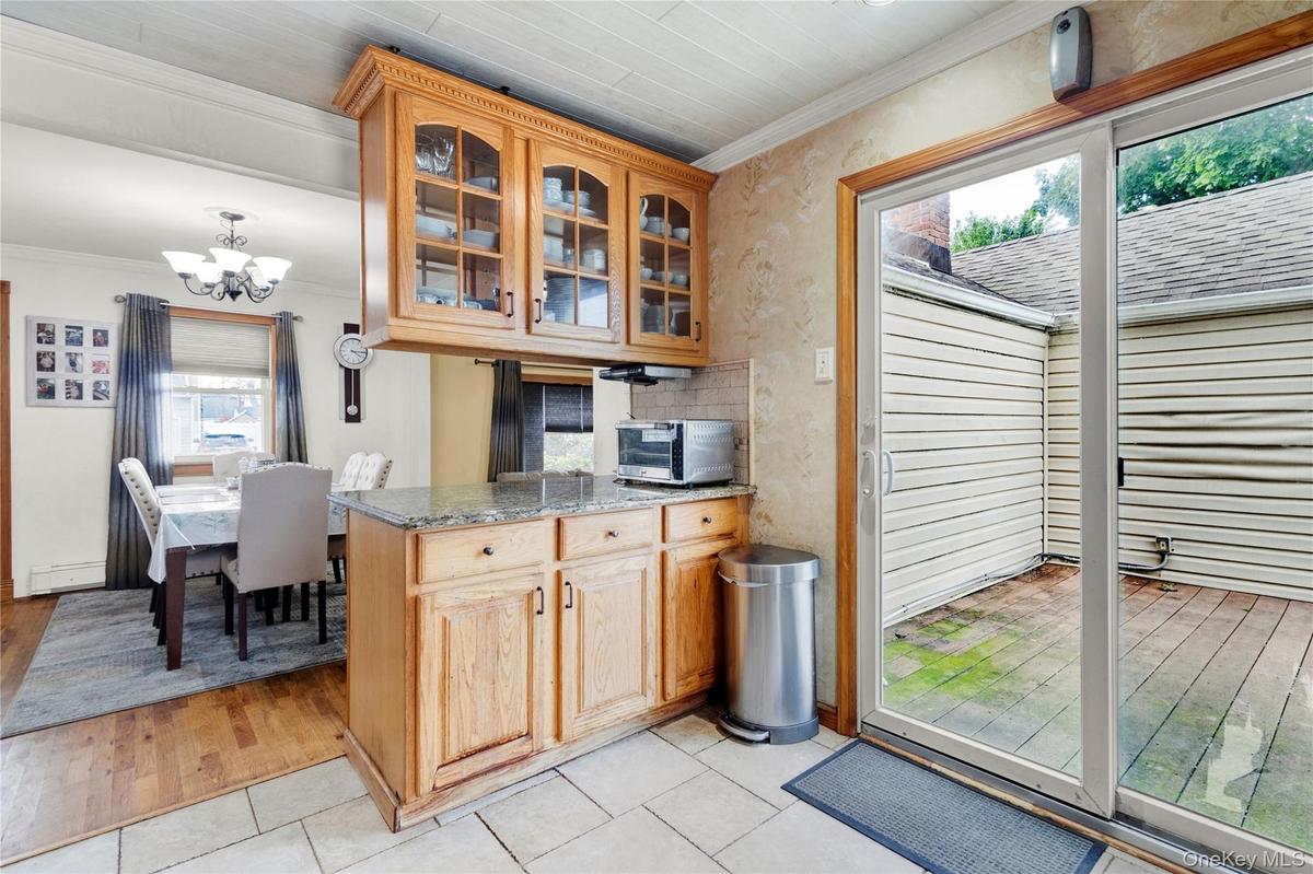 Kitchen featuring crown molding, light stone counters, a chandelier, light tile patterned flooring, and glass insert cabinets