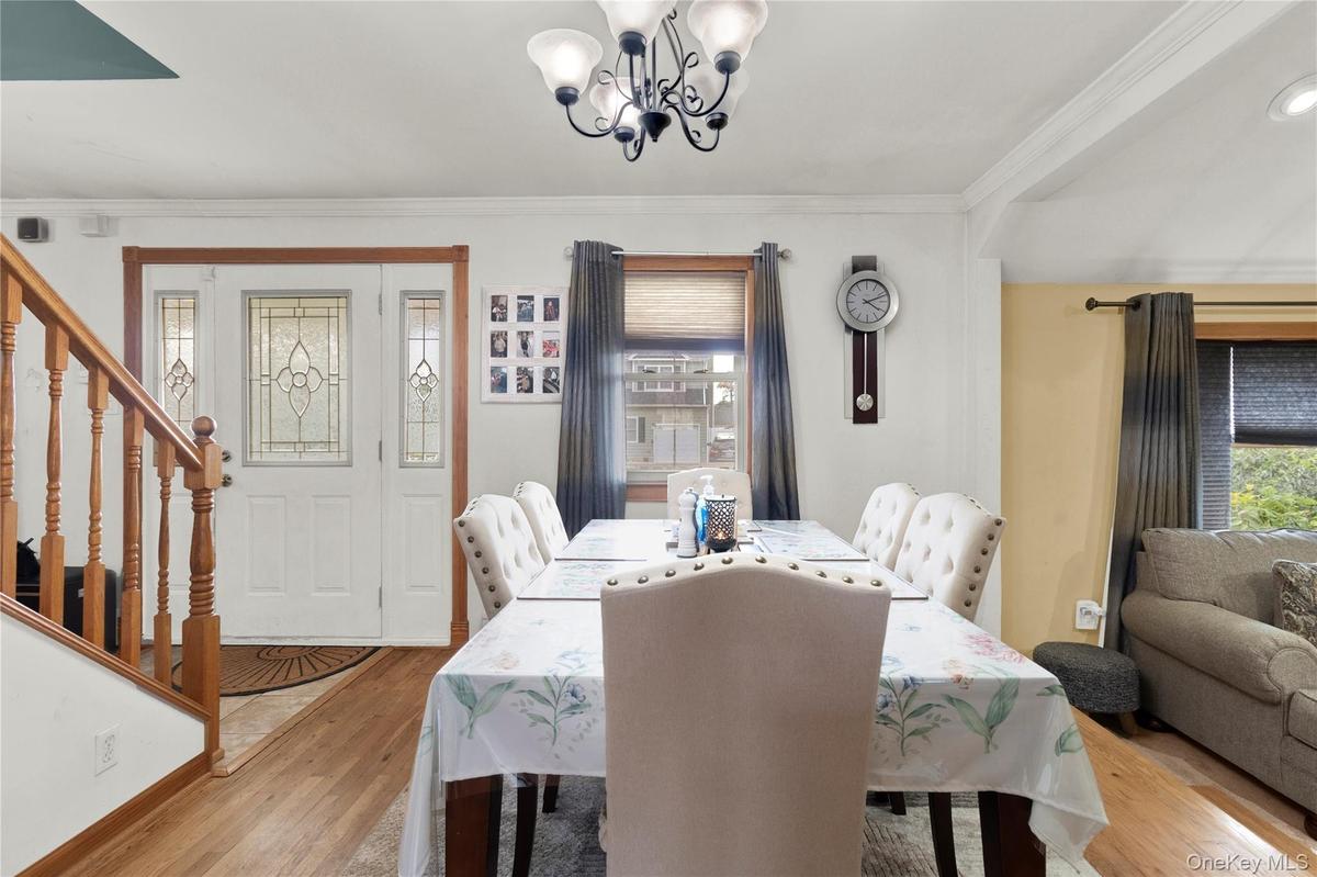 Dining space featuring ornamental molding, wood finished floors, a chandelier, and stairs
