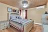 Bedroom featuring wooden ceiling, light wood finished floors, a wall unit AC, and ornamental molding
