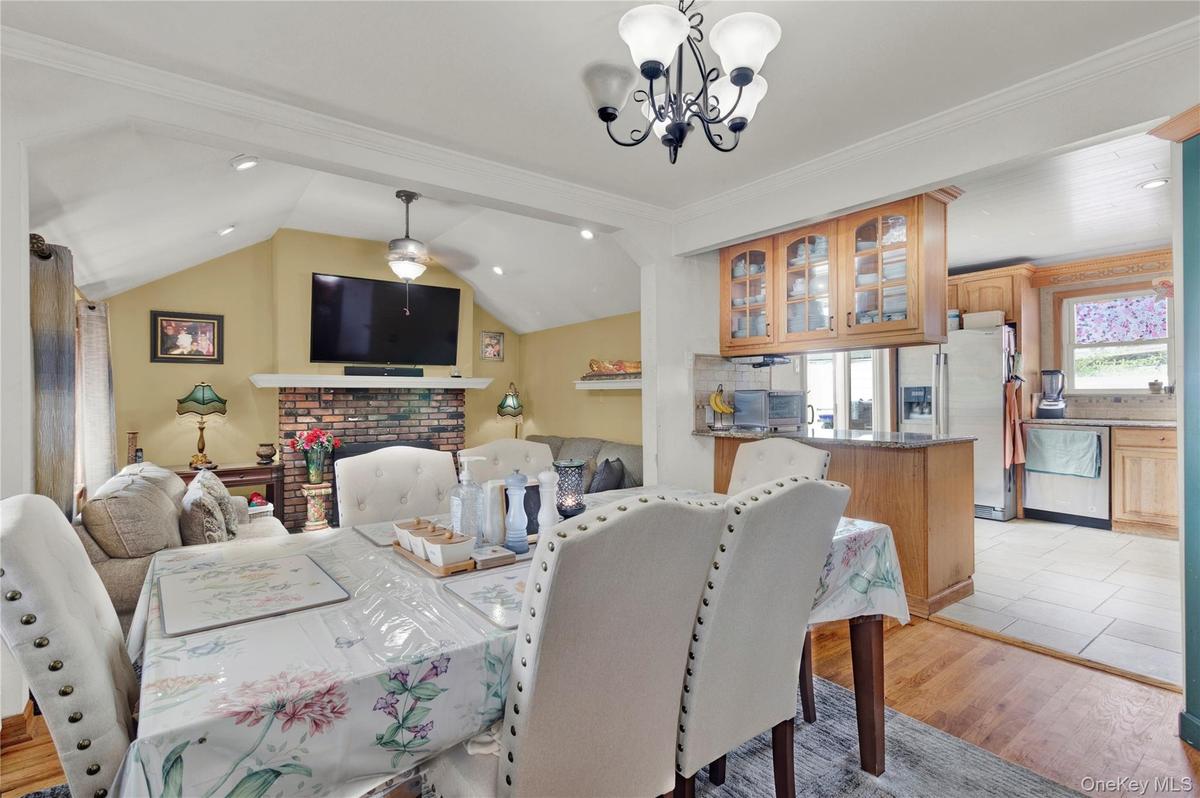 Dining area with a chandelier, light wood finished floors, lofted ceiling, ornamental molding, and recessed lighting