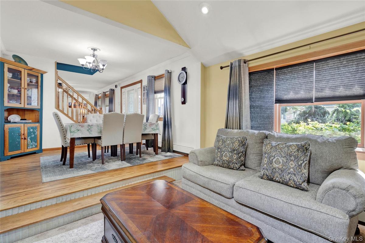 Living area with light wood-style flooring, a chandelier, and stairway
