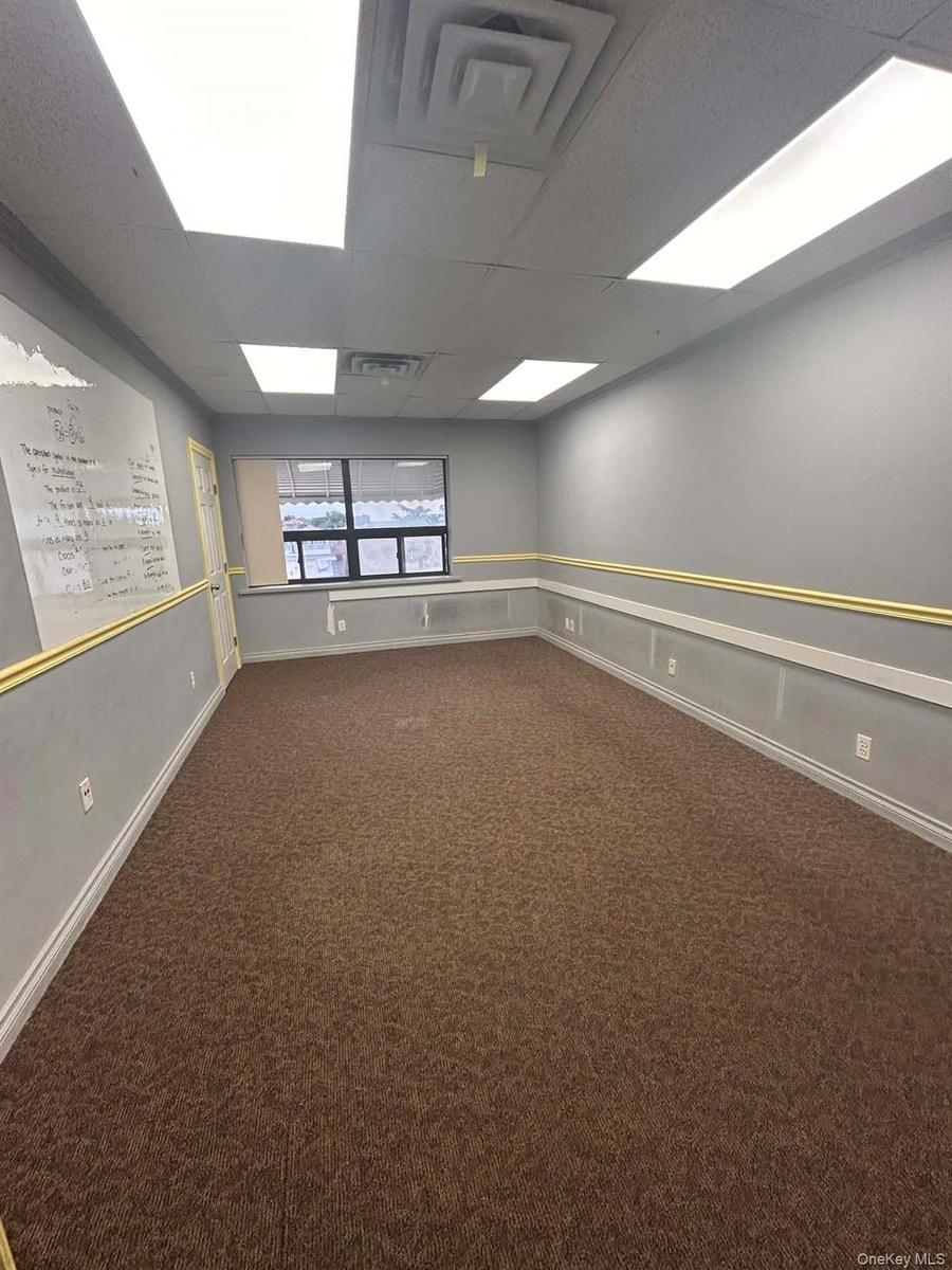 Spare room with a paneled ceiling and dark colored carpet