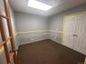 Empty room with dark carpet and a drop ceiling