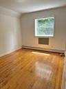 Unfurnished room featuring a baseboard heating unit, light wood-style flooring, and lofted ceiling