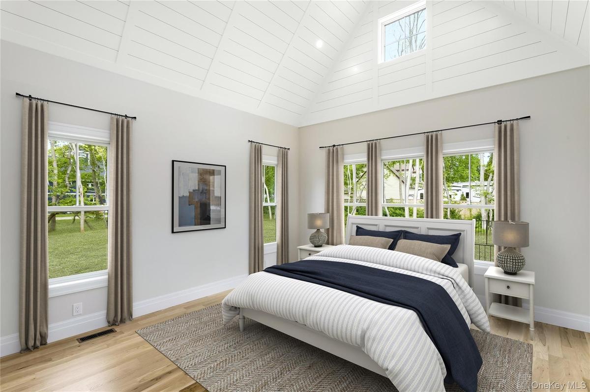 Primary Bedroom Staged featuring high vaulted ceiling, multiple windows, and light wood finished floors