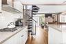 Kitchen with wall chimney exhaust hood, white cabinets, tasteful backsplash, stainless steel gas cooktop, and light stone counters