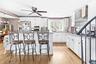 Kitchen with a kitchen breakfast bar, a kitchen island, white cabinets, and wall chimney range hood