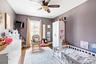 Bedroom featuring a crib, wood finished floors, and a ceiling fan