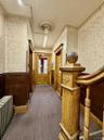 Corridor featuring wallpapered walls, radiator heating unit, wainscoting, and carpet floors