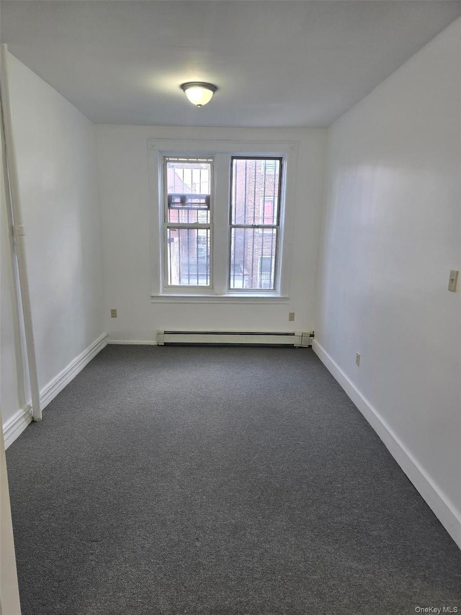 Empty room with carpet flooring and a baseboard radiator