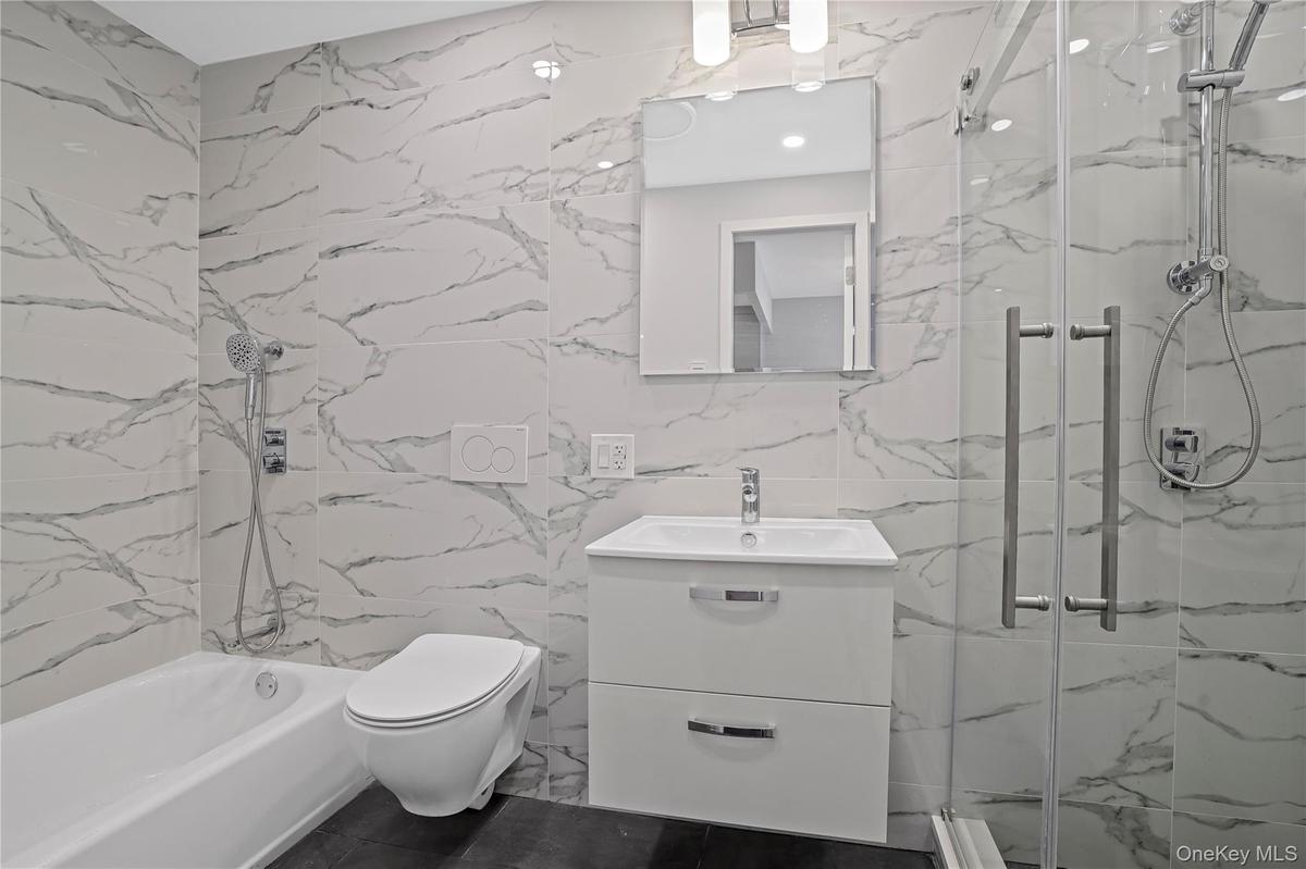 Full bathroom featuring a marble finish shower, vanity, and tile walls