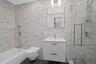 Full bathroom featuring a marble finish shower, vanity, and tile walls