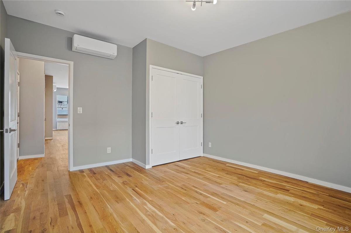 Unfurnished bedroom featuring light wood-style floors, a wall mounted air conditioner, and a closet