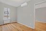 Unfurnished room featuring radiator heating unit, light wood finished floors, and an AC wall unit