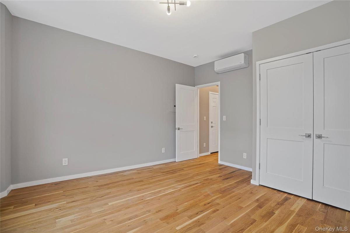 Unfurnished bedroom with light wood-style flooring, a wall unit AC, and a closet