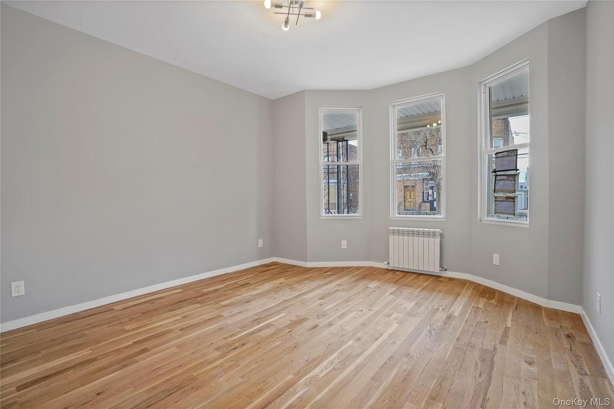 Unfurnished room with light wood-style flooring, plenty of natural light, and radiator heating unit