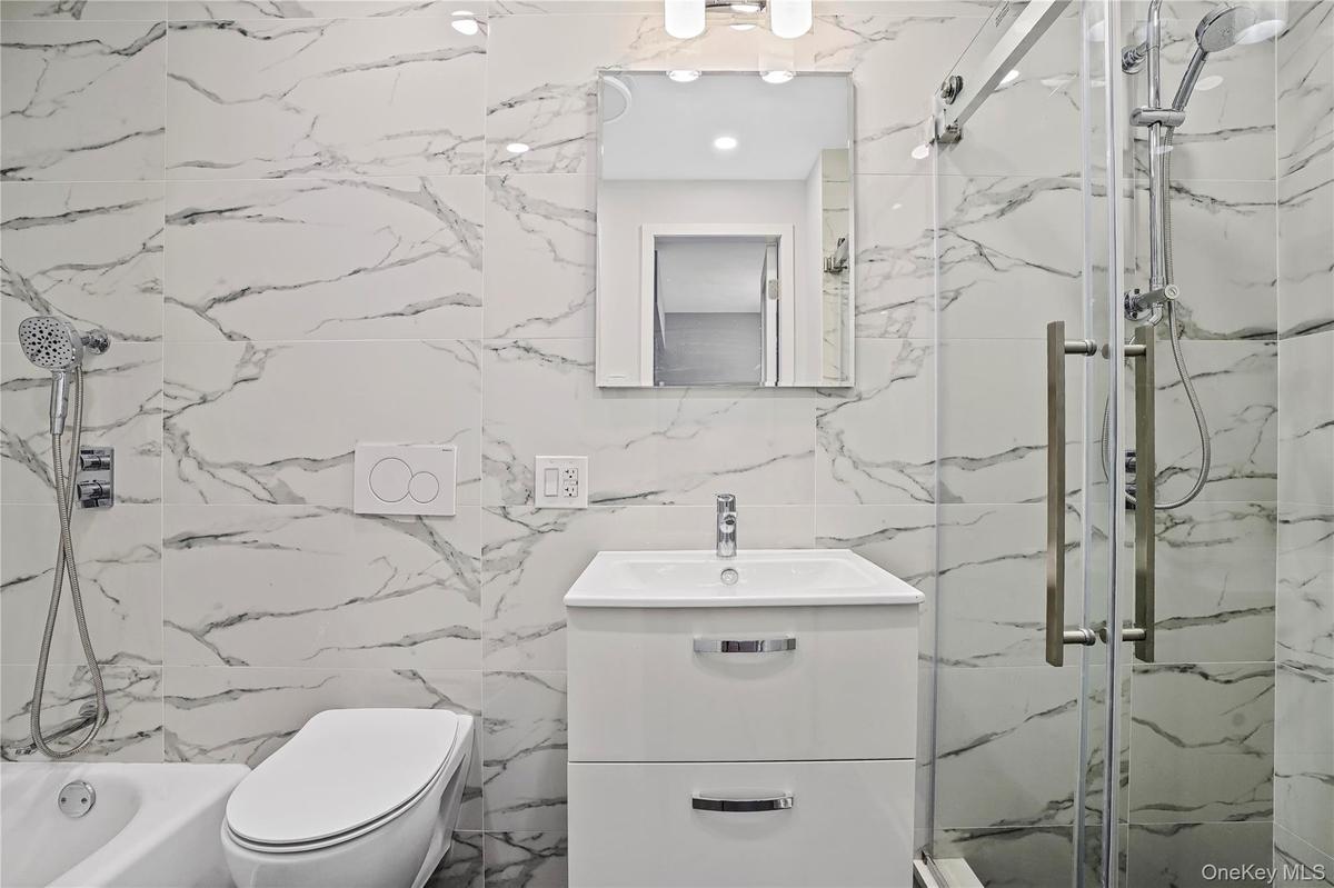 Full bath with a marble finish shower, vanity, tile walls, and a tub to relax in
