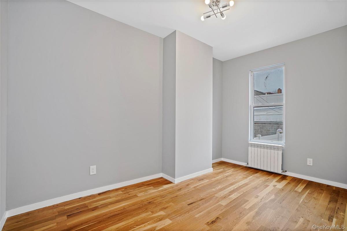 Unfurnished room with light wood-type flooring and radiator
