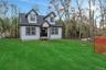 Cape cod-style house featuring a shingled roof and a front lawn