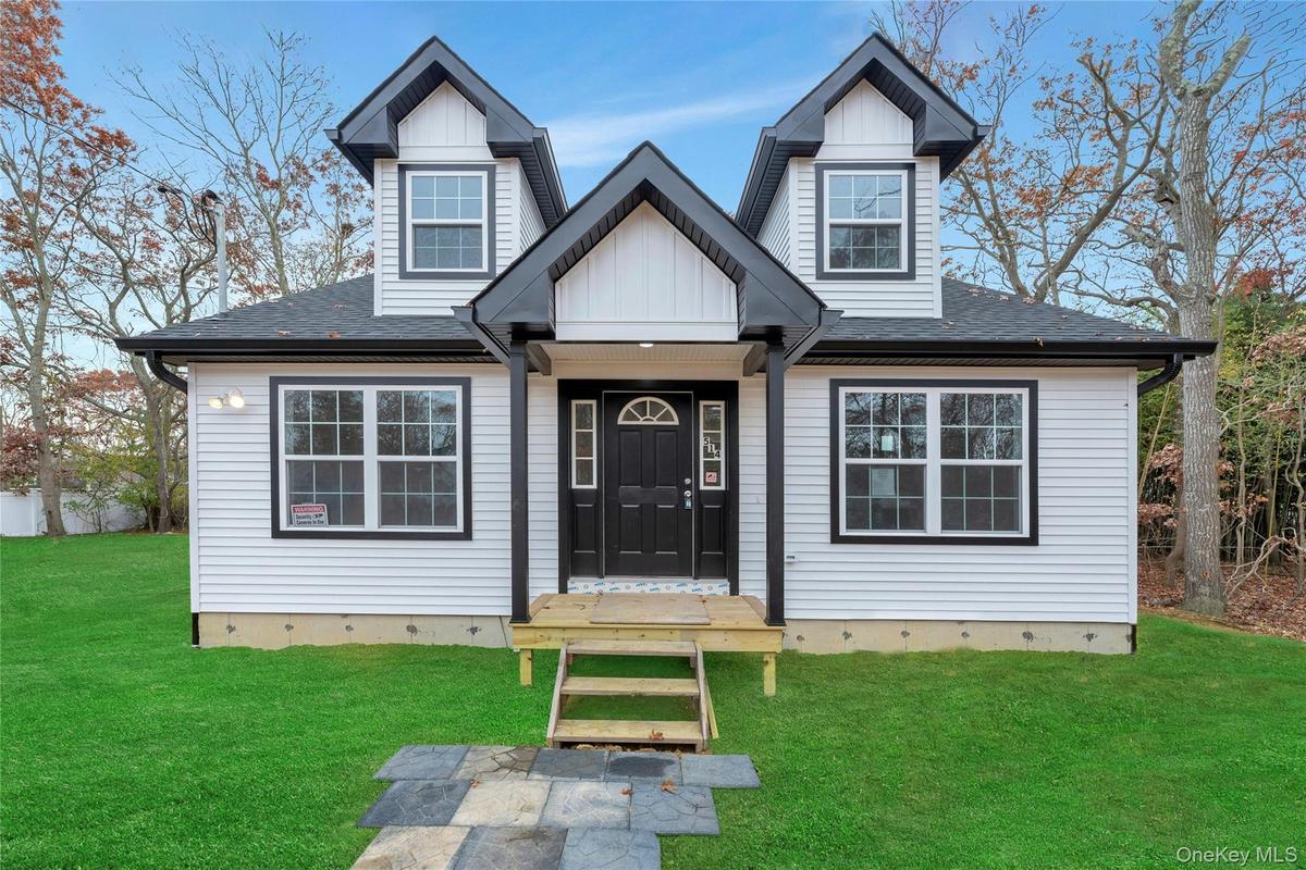 View of front of property featuring a front lawn, roof with shingles, and board and batten siding