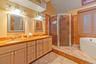 Bathroom featuring a stall shower, double vanity, vaulted ceiling, and a bath