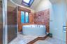 Full bath featuring a skylight, a garden tub, vaulted ceiling, a shower stall, and tile walls