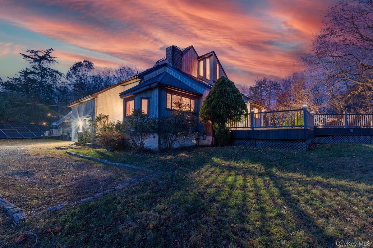 View of side of property with a chimney, a wooden deck, and a lawn