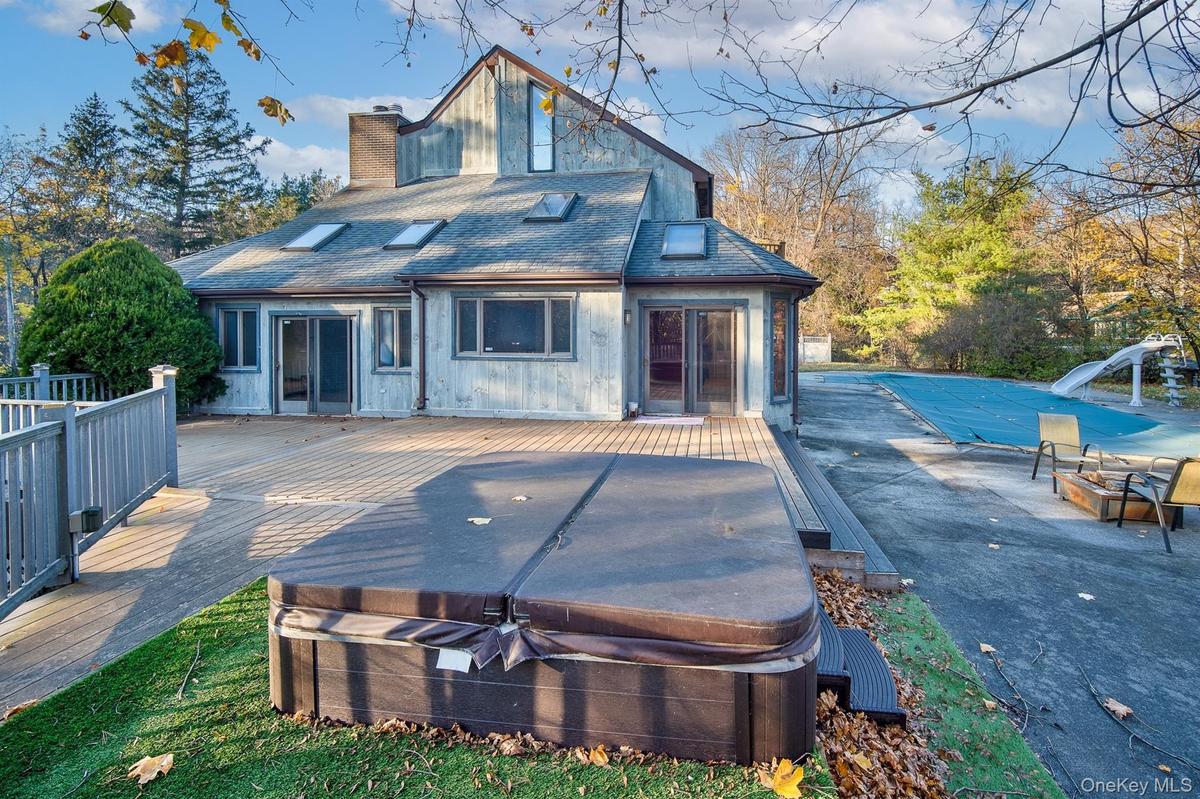 Back of house featuring a deck and a hot tub